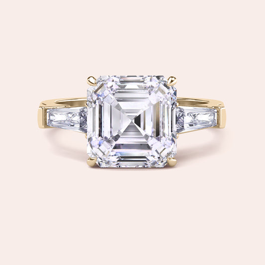 Luxurious yellow gold diamond ring showcasing a prominent emerald-cut center stone with side baguettes in a sleek setting