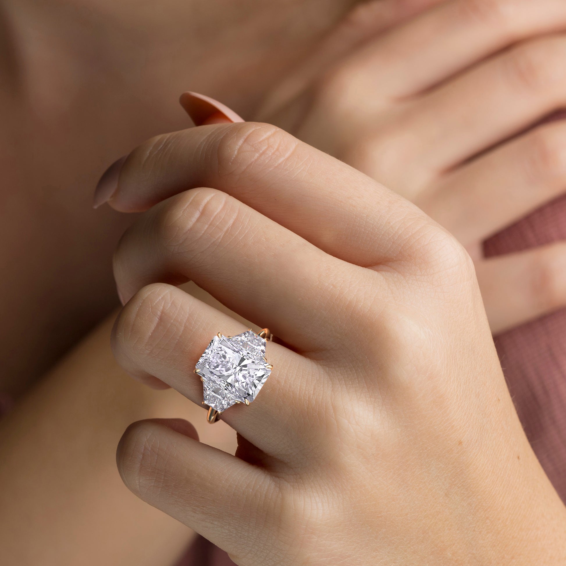 Close-up of a model wearing a stunning 14K or 18K yellow gold ring with a radiant-cut diamond and three trapezoid stones.|
#14KRecycledYellowGold
#18KRecycledYellowGold