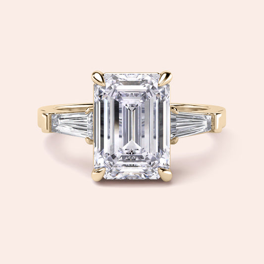 "14K or 18K yellow gold engagement ring with emerald-cut diamond and tapered baguette side stones."