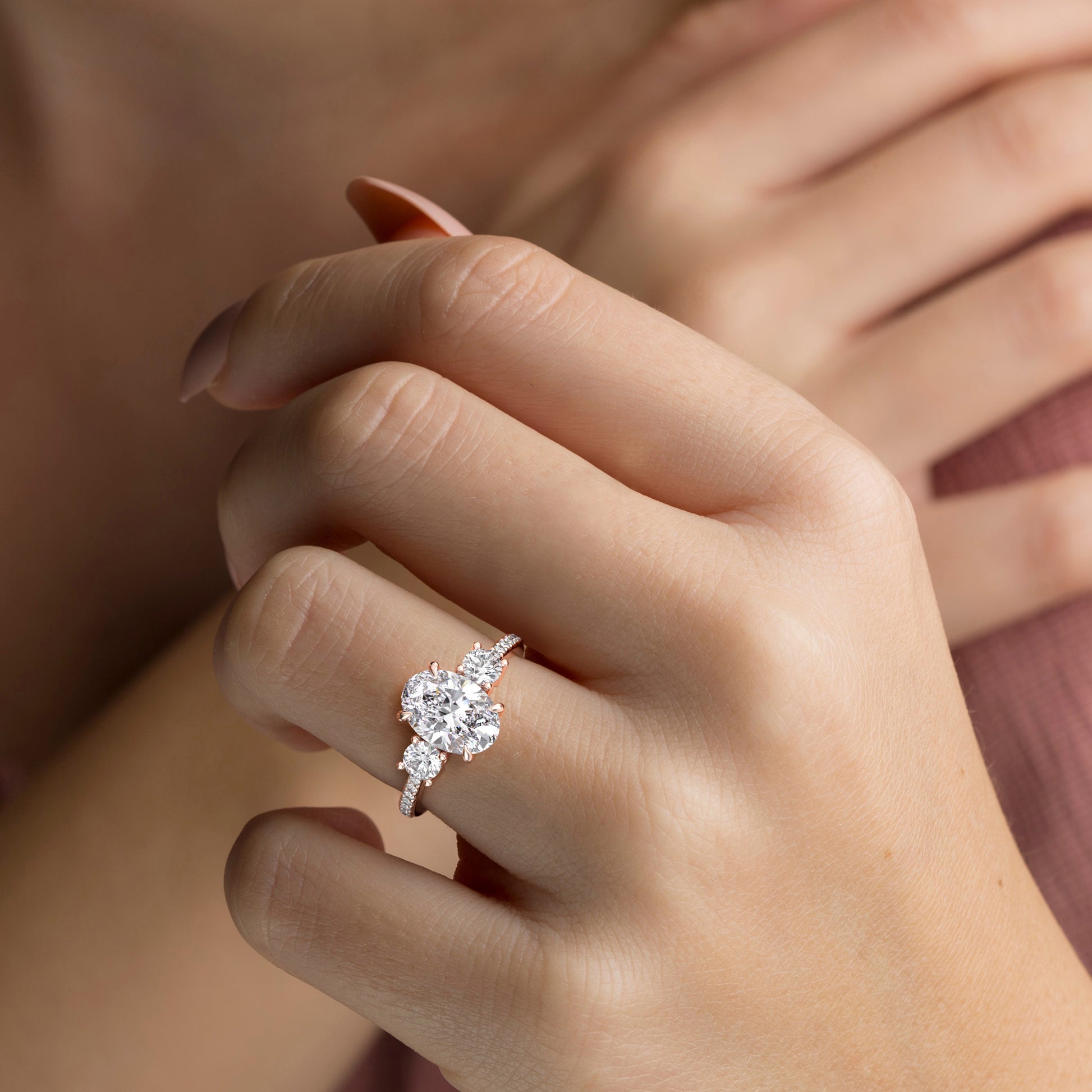 Elegant 14K rose gold engagement ring with three stones and pave detailing, worn on a model's hand, showcasing timeless beauty.|
#14KRecycledRoseGold
#18KRecycledRoseGold