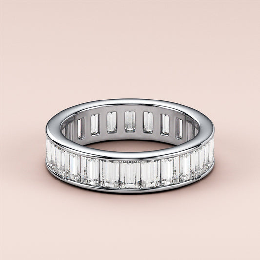 Elegant emerald channel eternity ring in 14K or 18K white gold, featuring baguette-cut diamonds, perfect for weddings.