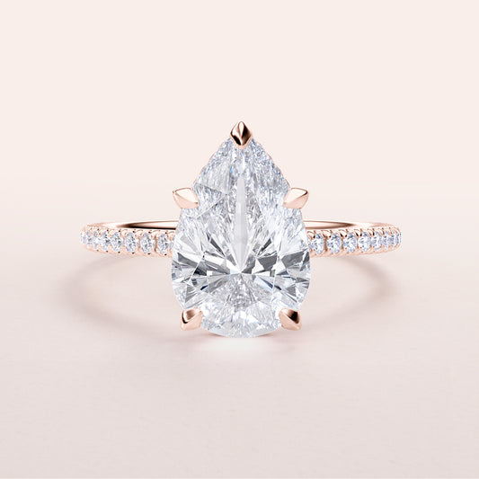 Elegant pear-shaped diamond engagement ring in rose gold, featuring a dazzling hidden halo and pave band, available in 14K & 18K.