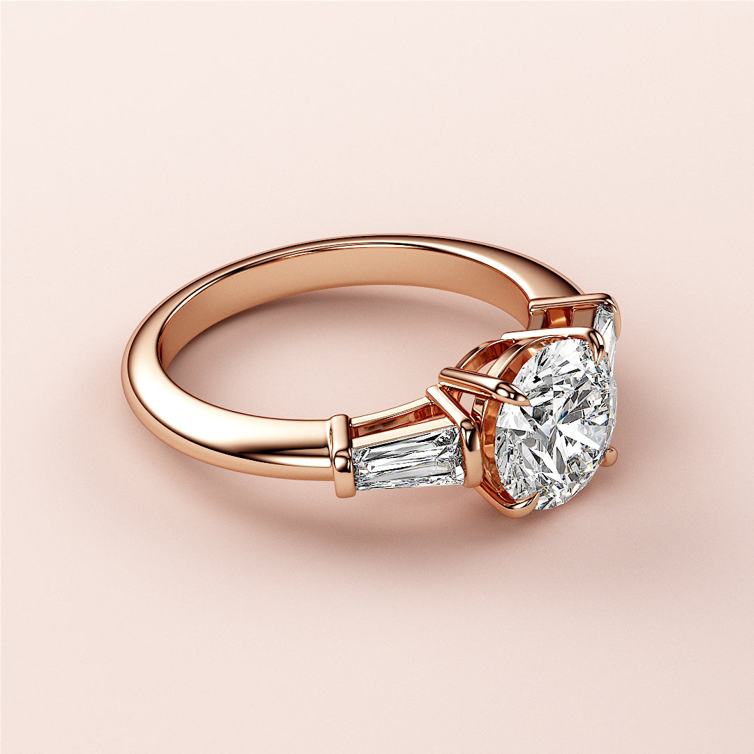 Elegant rose gold engagement ring featuring a round diamond center and tapered baguette side stones, available in 14K, 18K, or platinum.|
#14KRecycledRoseGold
#18KRecycledRoseGold