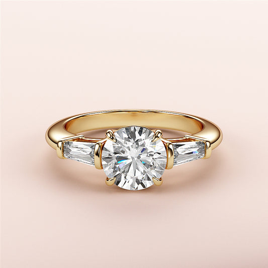 Elegant yellow gold engagement ring with round-cut diamond and tapered baguette accents, available in 14K, 18K, or platinum.