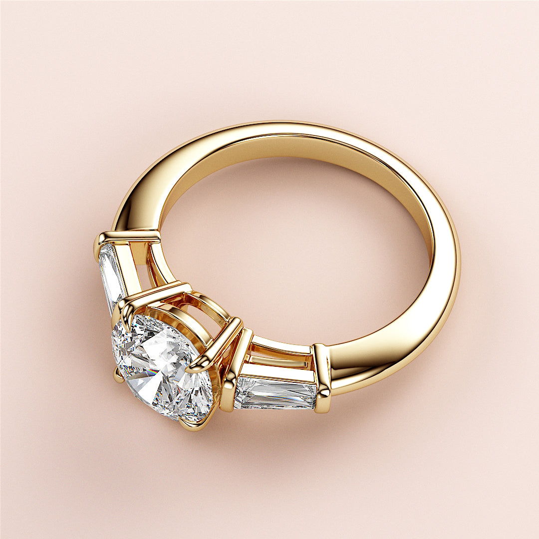 Elegant 14K/18K gold engagement ring featuring a central round diamond and tapered baguette side stones, perfect for proposals.|
#14KRecycledYellowGold
#18KRecycledYellowGold