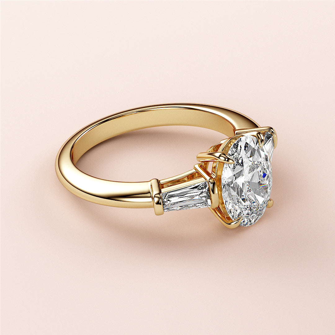 Elegant 14K yellow gold engagement ring featuring an oval-cut diamond and tapered baguette diamonds, not worn on a model.|
#14KRecycledYellowGold
#18KRecycledYellowGold