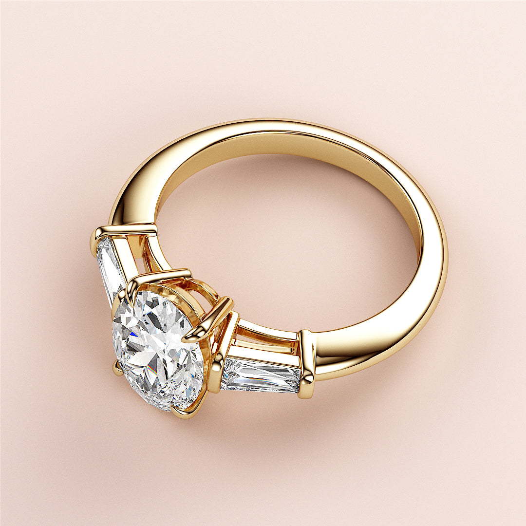 Elegant 14K or 18K gold engagement ring with oval design, round diamond center, and tapered baguette side stones.|
#14KRecycledYellowGold
#18KRecycledYellowGold