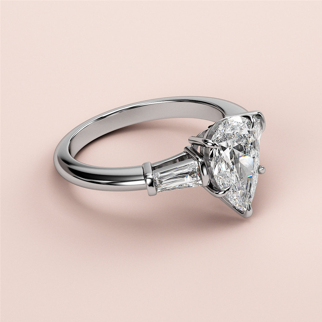 Elegant white gold engagement ring with a pear-shaped diamond center and tapered baguettes, perfect for a luxurious proposal.|
#14KRecycledWhiteGold
#18KRecycledWhiteGold
#Platinum