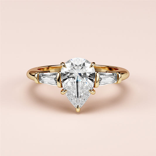 "Luxurious yellow gold pear-shaped diamond engagement ring with baguette side stones in a 14K or 18K setting."