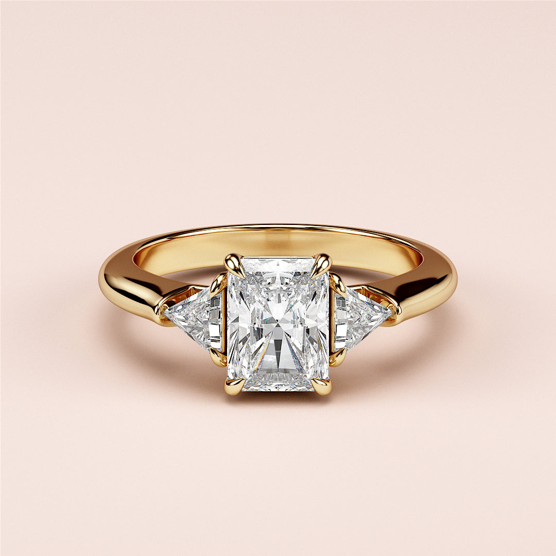 Elegant 14K yellow gold engagement ring featuring a radiant-cut diamond center stone and two trillion-cut side diamonds.|
#14KRecycledYellowGold
#18KRecycledYellowGold