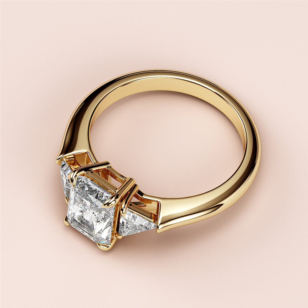 Elegant princess-cut diamond engagement ring with accents, in 14K or 18K yellow gold or platinum, showcasing three radiant stones.|
#14KRecycledYellowGold
#18KRecycledYellowGold