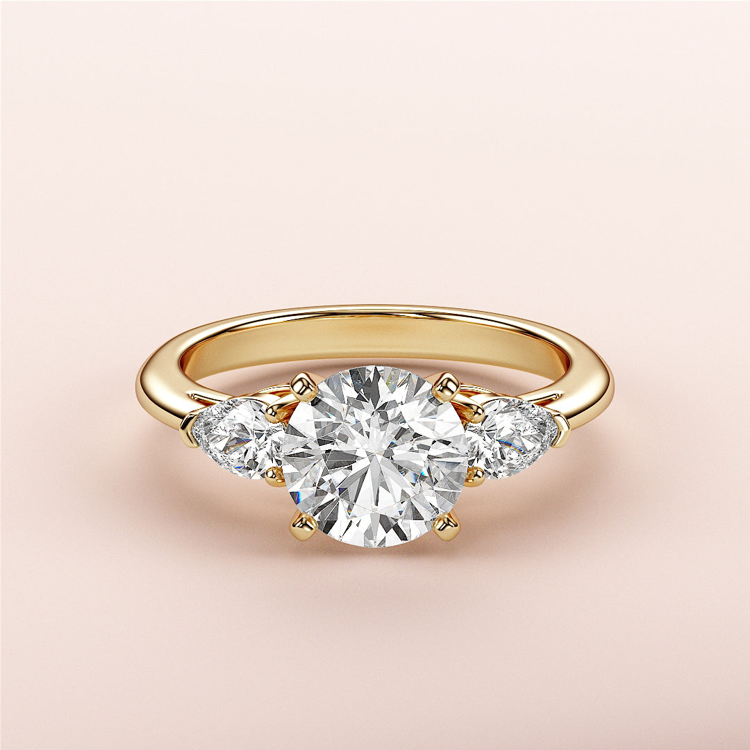 Exquisite 14K/18K gold engagement ring with round diamond center and pear-shaped side stones for a timeless look.|
#14KRecycledYellowGold
#18KRecycledYellowGold