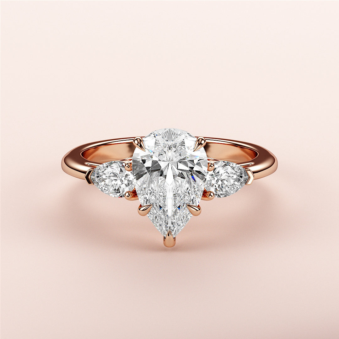 Elegant 14K or 18K rose gold pear-shaped diamond engagement ring with a central diamond and two smaller stones.|
#14KRecycledRoseGold
#18KRecycledRoseGold