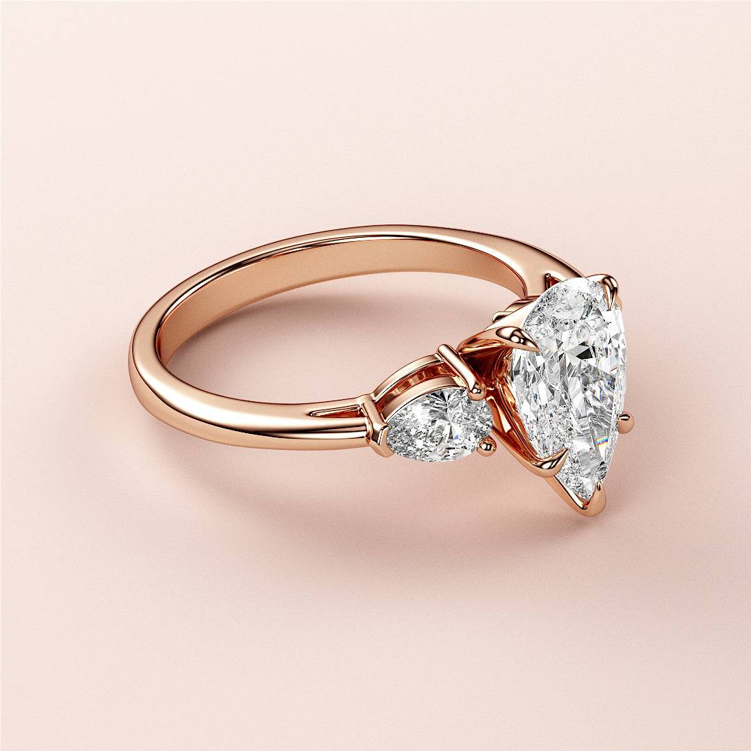 Elegant 14K rose gold engagement ring with a Marquise-cut diamond center and pear-shaped accents, beautifully crafted design.|
#14KRecycledRoseGold
#18KRecycledRoseGold