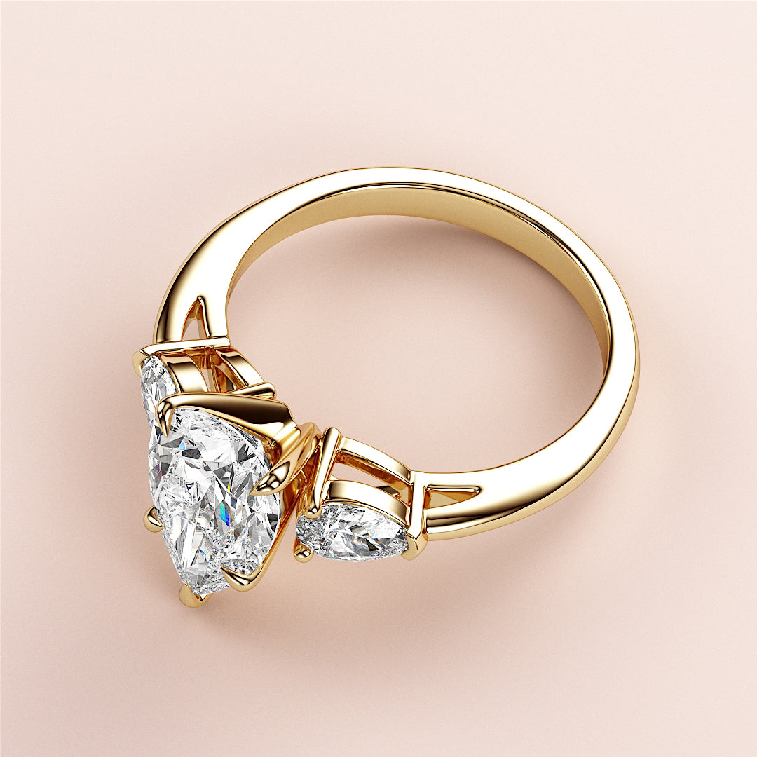 Elegant 14K or 18K gold engagement ring with pear-shaped diamond center and two smaller side stones, perfect for timeless proposals.|
#14KRecycledYellowGold
#18KRecycledYellowGold