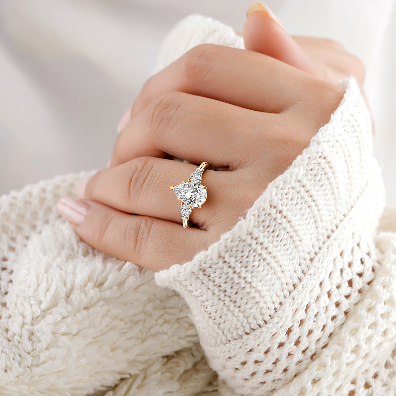 14K yellow gold pear three stone ring with dazzling trillion-cut diamond, elegantly worn on a model's hand in a cozy white sweater.|
#14KRecycledYellowGold
#18KRecycledYellowGold