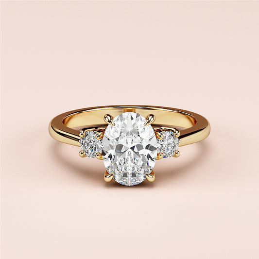 Oval-shaped engagement ring featuring two round side stones, set in 14K or 18K yellow gold or platinum band.