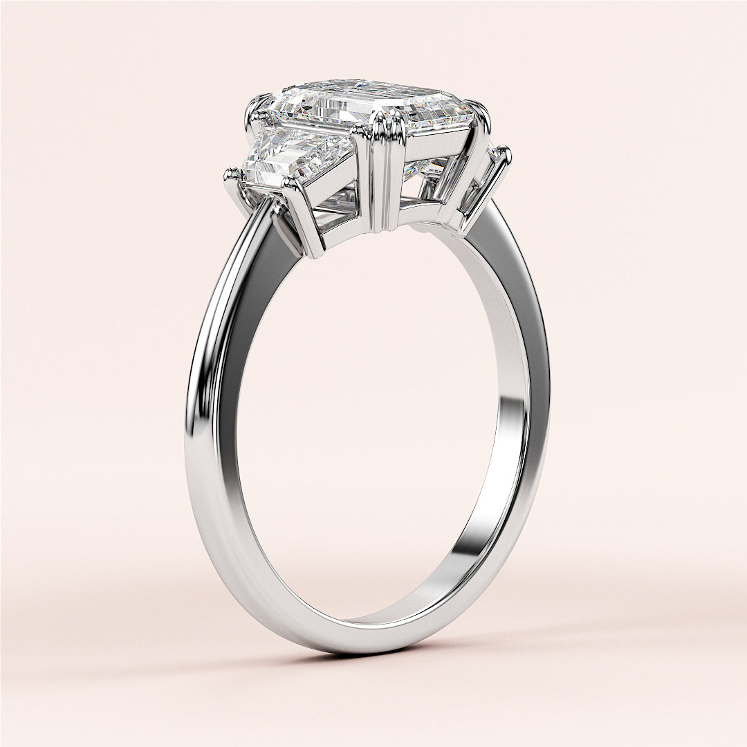 Elegant 14K or 18K white gold or platinum engagement ring with emerald three-stone trapezoid setting on a neutral background.|
#14KRecycledWhiteGold
#18KRecycledWhiteGold
#Platinum