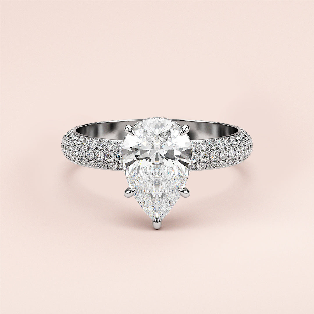 Elegant pear-shaped diamond engagement ring in 14K or 18K gold or platinum, adorned with smaller diamonds on a blush background.|
#14KRecycledWhiteGold
#18KRecycledWhiteGold
#Platinum