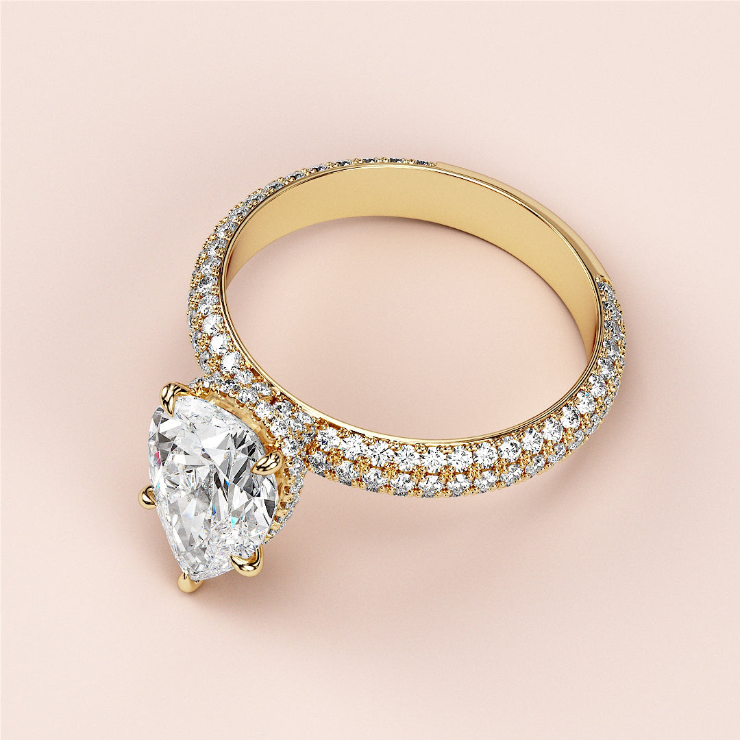 14K gold engagement ring featuring a pear-shaped diamond with a pave band, elegantly worn on a model's hand.|
#14KRecycledYellowGold
#18KRecycledYellowGold