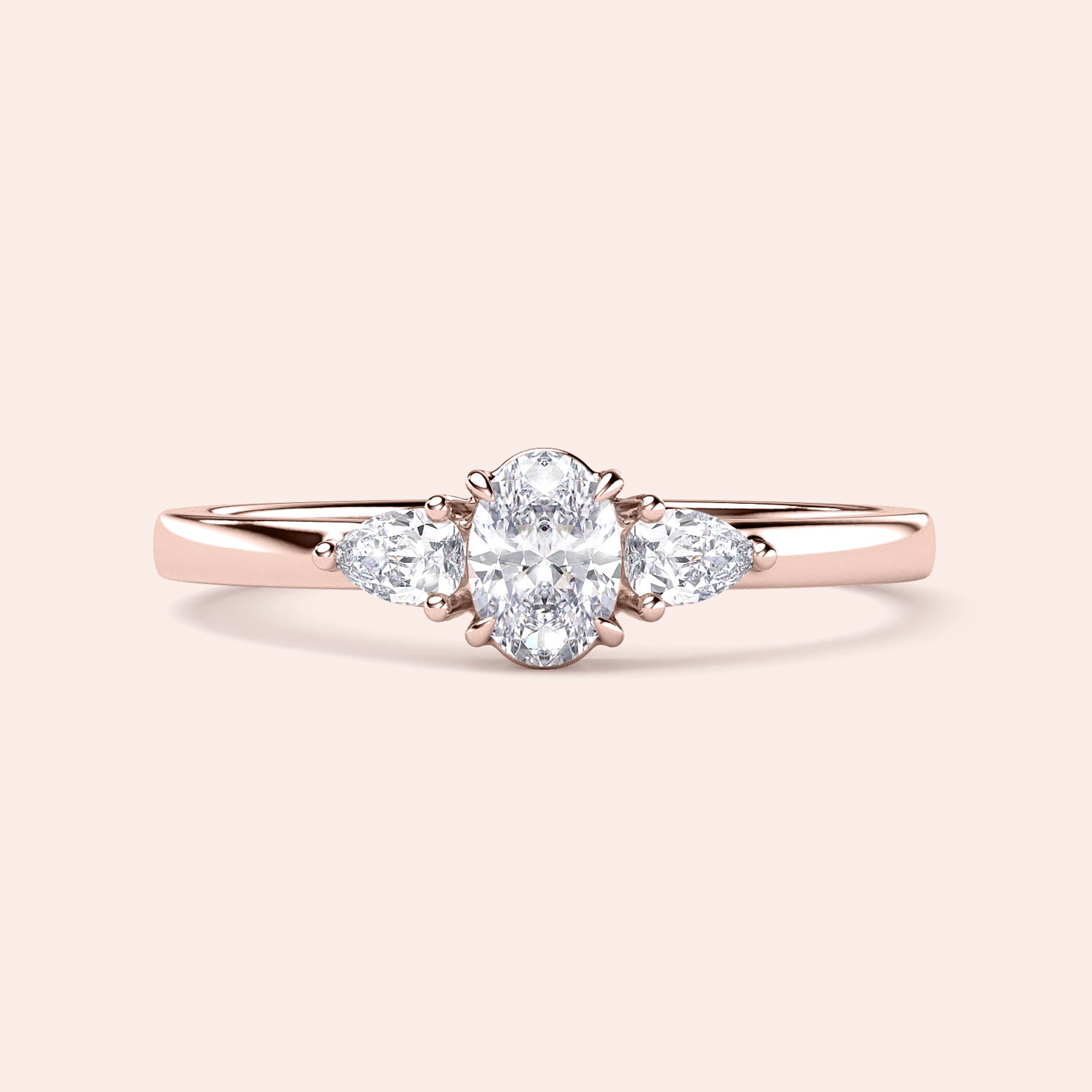 Elegant 14K rose gold engagement ring featuring an oval diamond and pear-shaped side stones, perfect for a timeless look.|
#14KRecycledRoseGold
#18KRecycledRoseGold