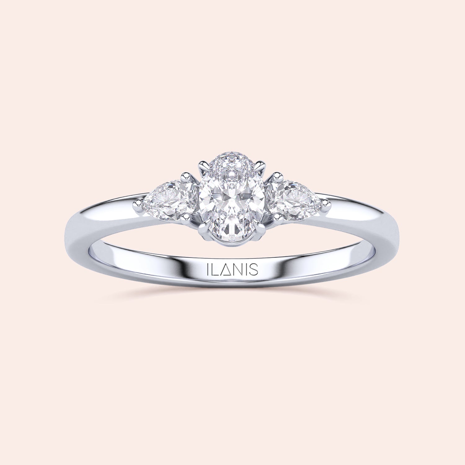Elegant 14K or 18K gold three-stone engagement ring with oval diamond and pear-shaped accents on a cream background.|
#14KRecycledWhiteGold
#18KRecycledWhiteGold
#Platinum