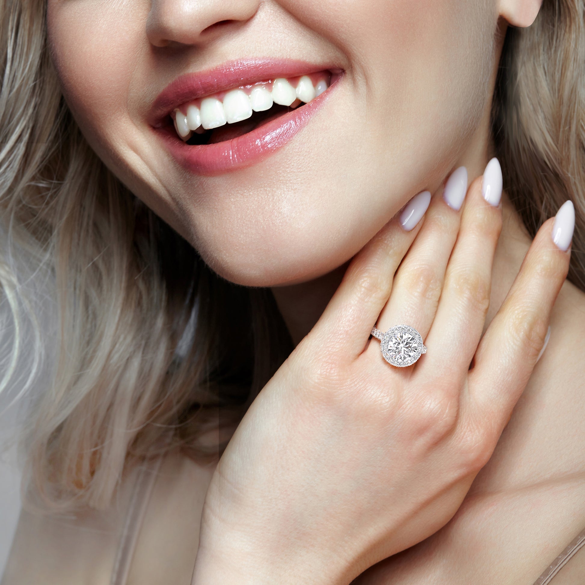 White gold round halo diamond engagement ring on smiling model hand, elegant bridal jewelry close-up | #14KRecycledWhiteGold #18KRecycledWhiteGold #Platinum
