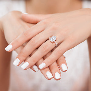 Oval diamond engagement ring on hand, rose gold pavé bridal ring close-up with white manicure 