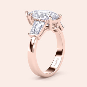 Pear shaped diamond engagement ring in rose gold, side angle showcasing three stone design with tapered baguette side diamonds 