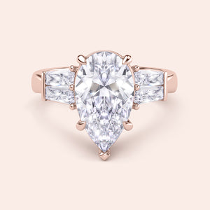 Pear cut diamond three stone ring in rose gold, top view with elegant prong setting and baguette side diamonds 