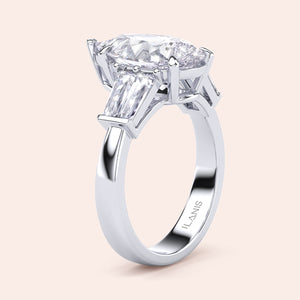 Pear cut diamond three stone engagement ring in white gold, side profile showcasing elevated setting and tapered baguette side stones 