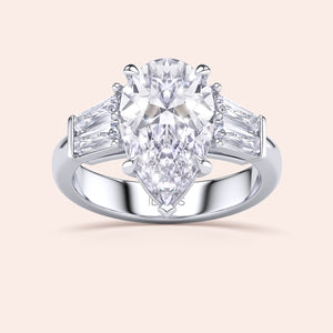 Pear shaped diamond engagement ring in white gold with tapered baguette side stones, classic three stone design with brilliant center diamond 