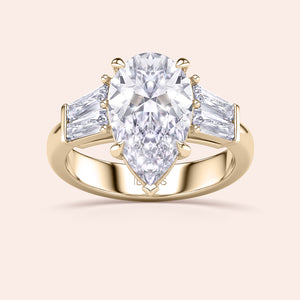 Pear diamond three stone ring in yellow gold, top view highlighting symmetry of center stone and baguette side diamonds 