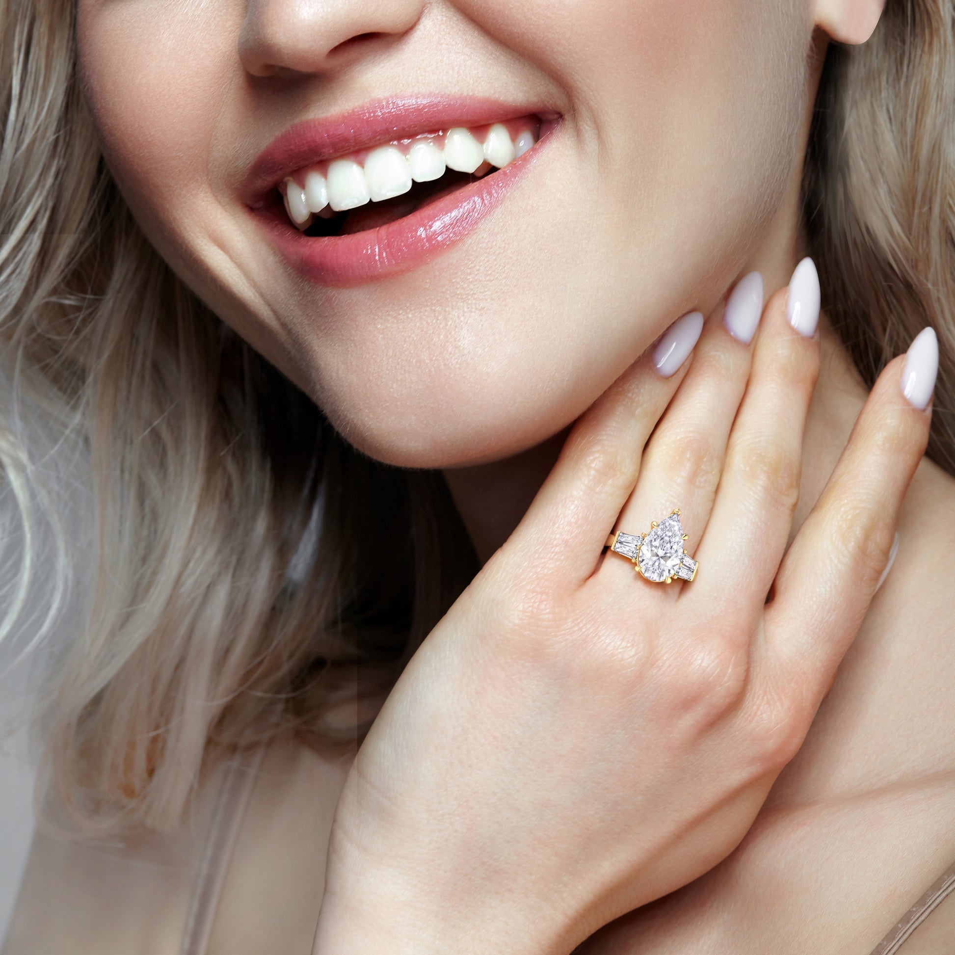 Pear diamond engagement ring in yellow gold worn on hand near face, showcasing sparkle and modern elegance | #14KRecycledYellowGold #18KRecycledYellowGold