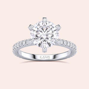 Top view close-up of white gold or platinum round diamond engagement ring with pavé band, emphasizing cut precision, sparkle and prong accents 