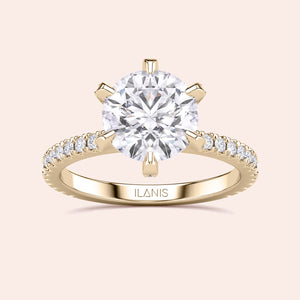 Top view close-up of yellow gold round diamond engagement ring with pavé band, emphasizing cut precision, sparkle and prong accents 