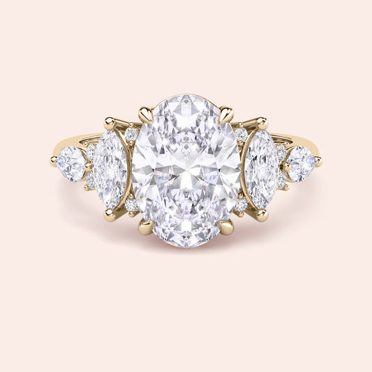 Yellow gold oval diamond three stone engagement ring side profile with pear side stones, elevated setting and handcrafted fine jewelry detail 