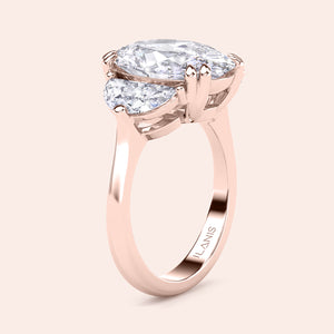 Oval diamond three stone engagement ring in rose gold with pear shaped side stones, side profile showcasing elevated basket setting and refined craftsmanship 