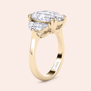 Oval diamond three stone engagement ring in yellow gold with pear shaped side stones, side profile showcasing elevated basket setting and refined craftsmanship 
