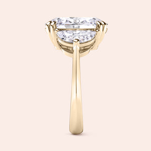 Oval diamond engagement ring in yellow gold with three stone setting, side angle showing prong setting and clean elegant structure 
