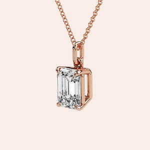 A stylish woman wearing a solitaire emerald-cut diamond pendant in rose gold. The pendant’s elongated shape and clean facets make it a perfect choice for those who love modern elegance with a vintage touch.
