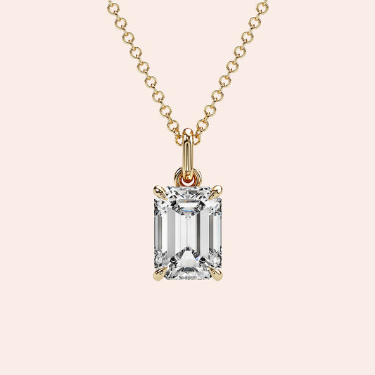 A close-up of a solitaire emerald-cut diamond pendant in a four-prong yellow gold setting. This elegant and modern design enhances the diamond’s brilliance while maintaining a minimalist aesthetic.
