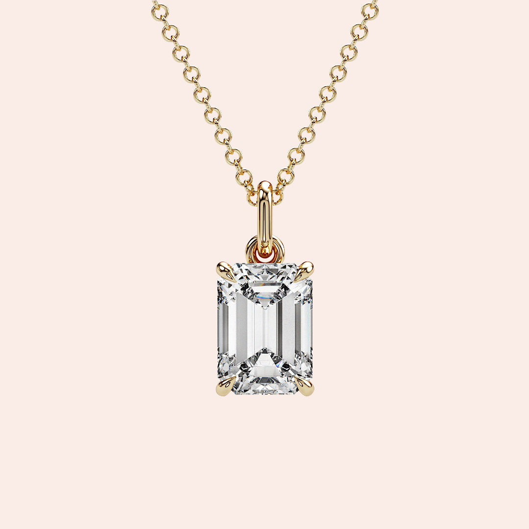 A close-up of a solitaire emerald-cut diamond pendant in a four-prong yellow gold setting. This elegant and modern design enhances the diamond’s brilliance while maintaining a minimalist aesthetic.
