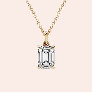 A close-up of a solitaire emerald-cut diamond pendant in a four-prong yellow gold setting. This elegant and modern design enhances the diamond’s brilliance while maintaining a minimalist aesthetic.

