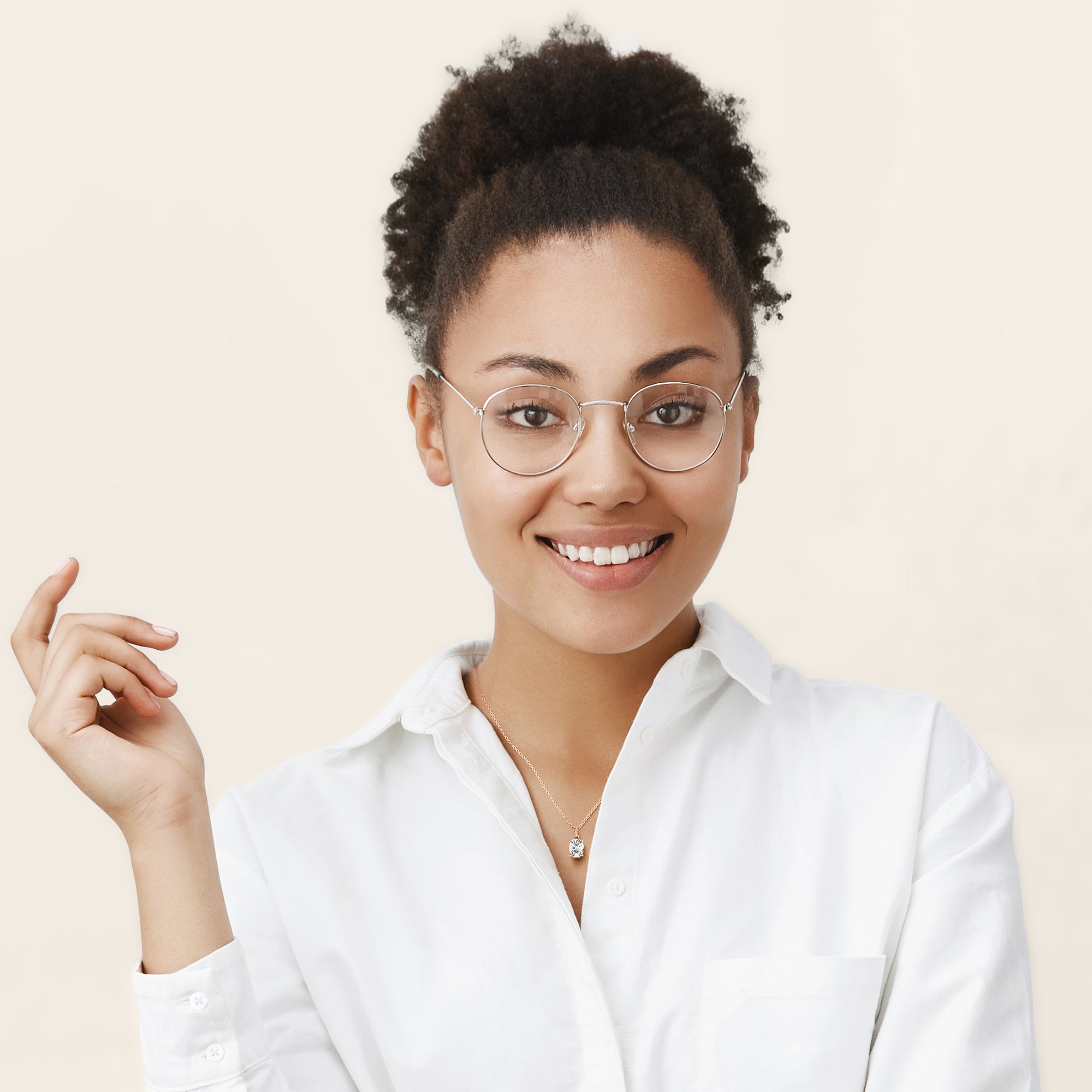 A stylish woman showcases an oval-cut diamond solitaire pendant in 14K or 18K rose gold. The soft pink hues of the gold complement the brilliance of the diamond, creating a romantic and elegant look.
