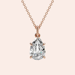 A close-up of a pear-shaped diamond solitaire pendant, securely set in a four-prong rose gold setting. The diamond’s unique shape exudes grace and brilliance. 