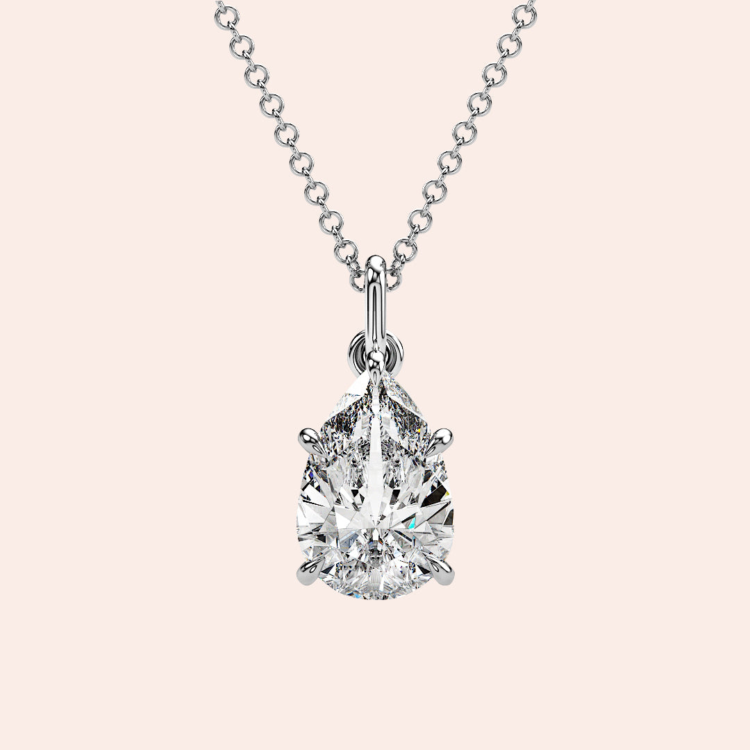 A radiant woman showcasing a pear-shaped diamond solitaire pendant in white gold. This delicate yet striking design enhances her look with understated elegance.
