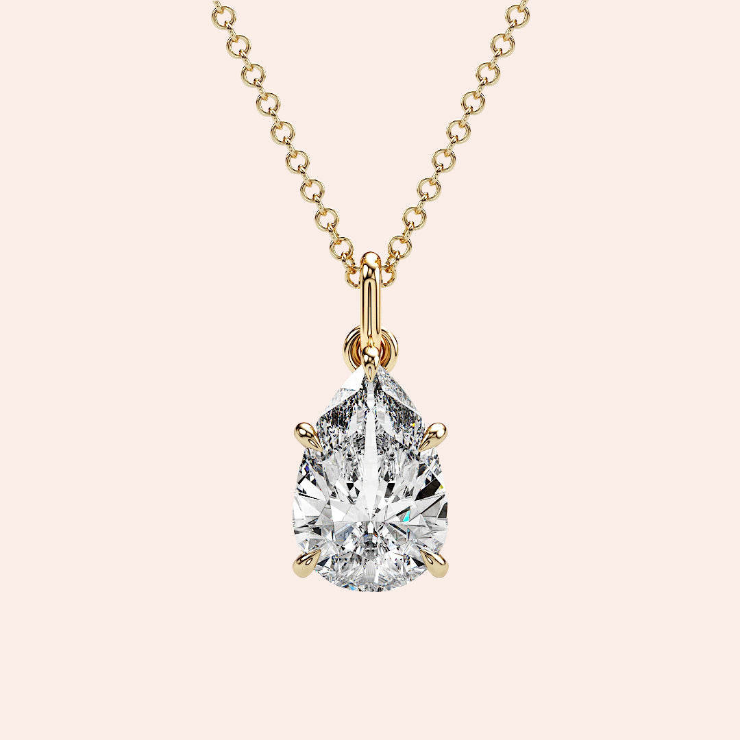 A close-up of a pear-shaped diamond solitaire pendant, set in a delicate four-prong yellow gold setting. This timeless design highlights the natural beauty and fire of the diamond. 