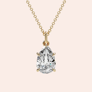 A close-up of a pear-shaped diamond solitaire pendant, set in a delicate four-prong yellow gold setting. This timeless design highlights the natural beauty and fire of the diamond. 