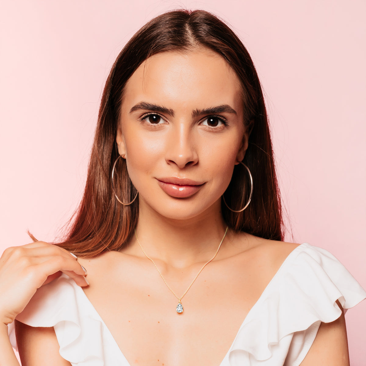  radiant woman styled with a pear-shaped diamond solitaire pendant in yellow gold, effortlessly combining sophistication and charm. The brilliant-cut diamond catches the light beautifully, making it a versatile everyday accessory.
